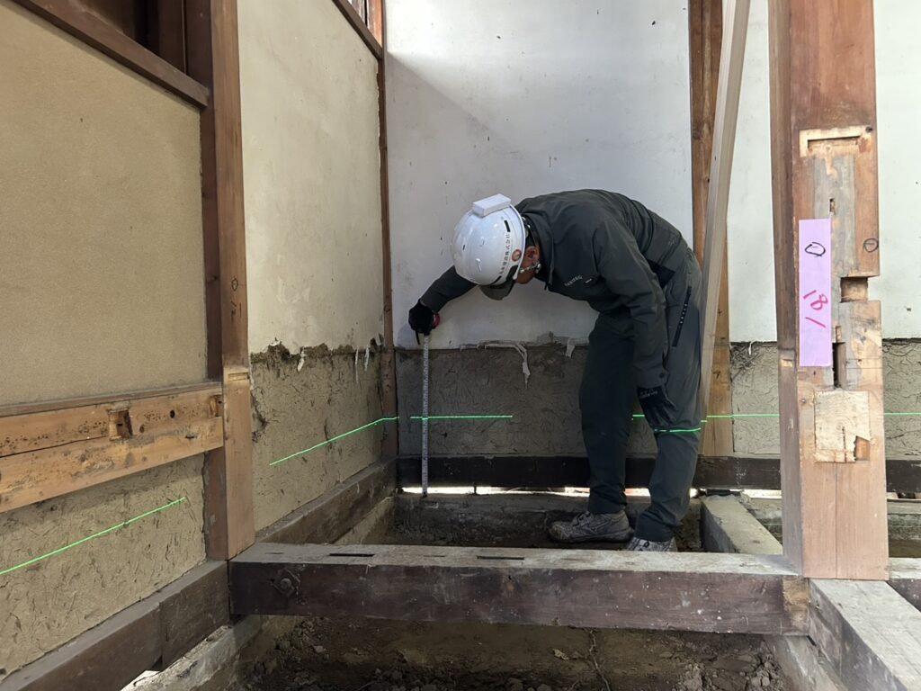 床の高さを変えるため、レーザーで基準の高さを出して測定している様子